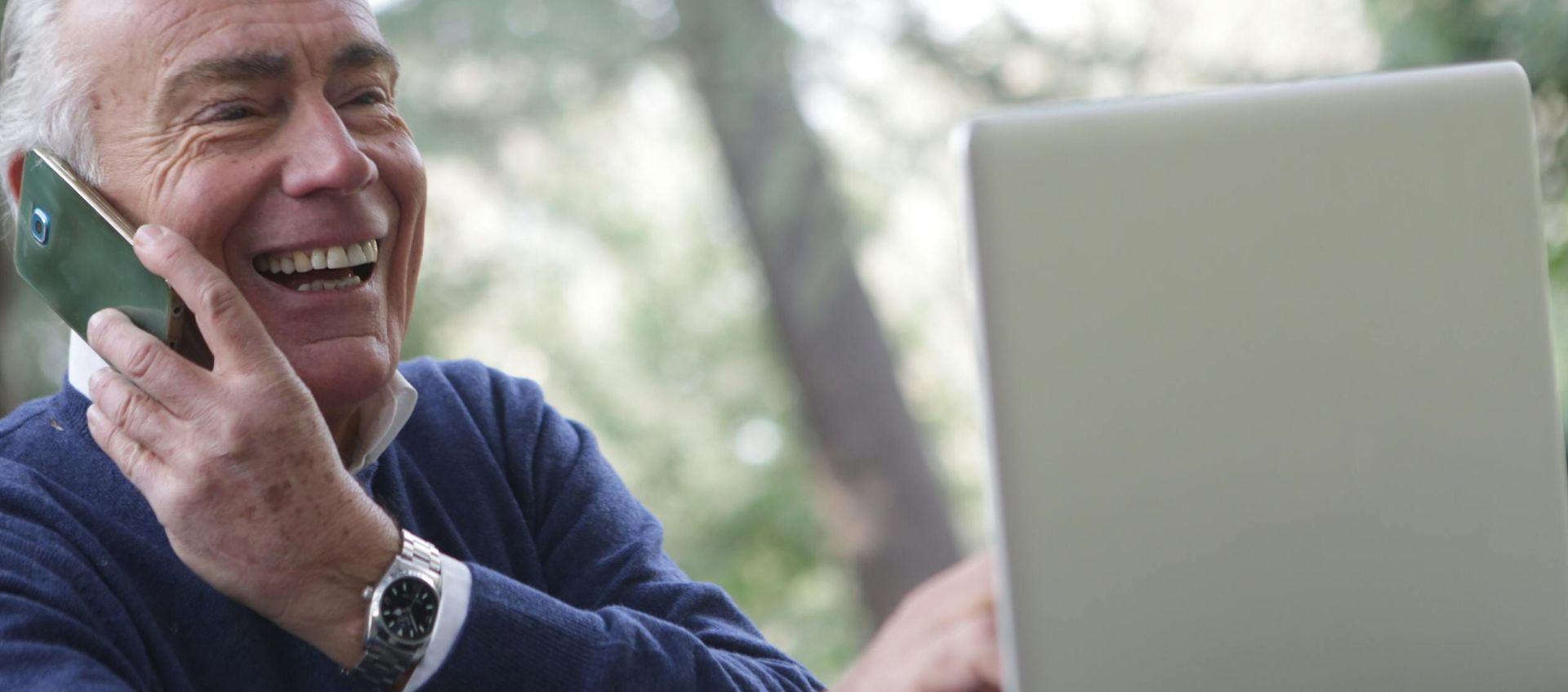 Man in Blue Long Sleeve Sweater Using Cellphone