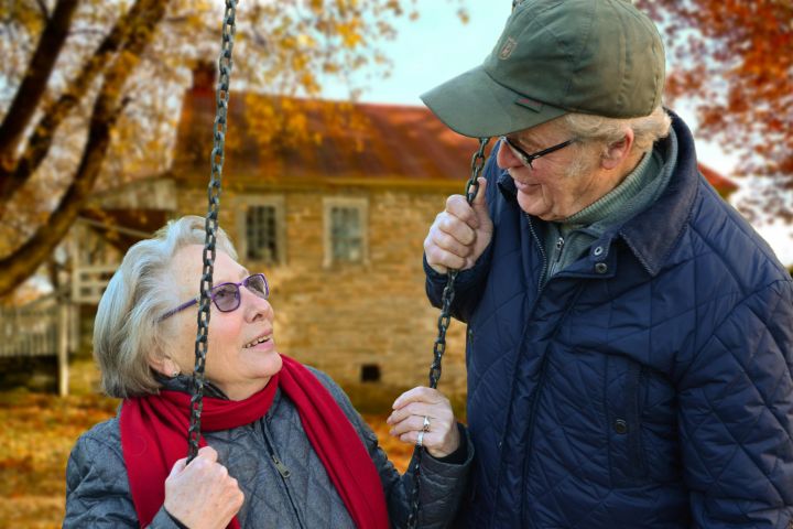 Man Standing Beside Woman on Swing