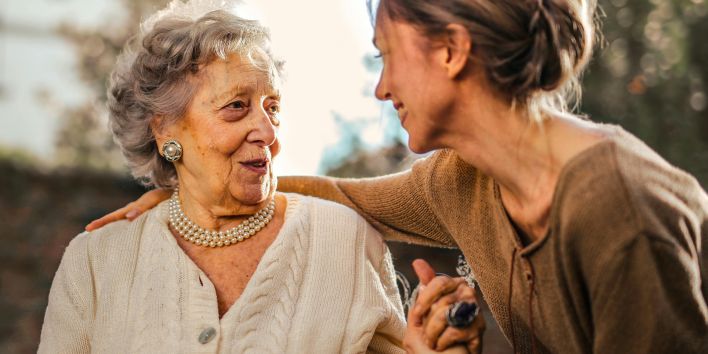 Joyful adult daughter greeting happy surprised senior mother in garden